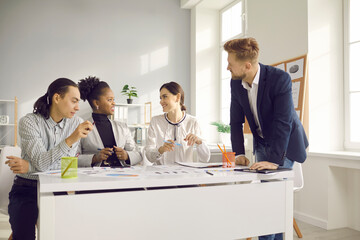 Happy diverse company workers sitting at office desk and discussing project in group meeting. Team...