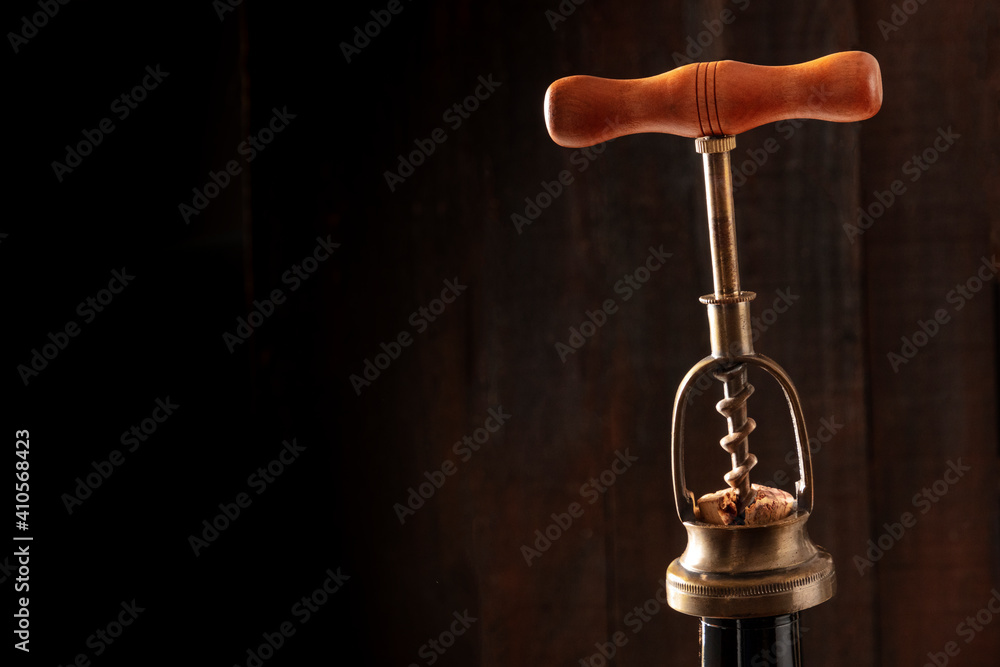 Wall mural Wine design template. An old corkscrew, pulling out a cork from a bottle on a dark background, with a place for text