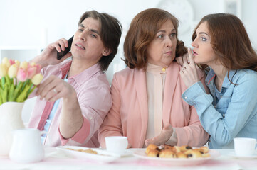 happy family of three spending time together at dinner table with cookies and tea