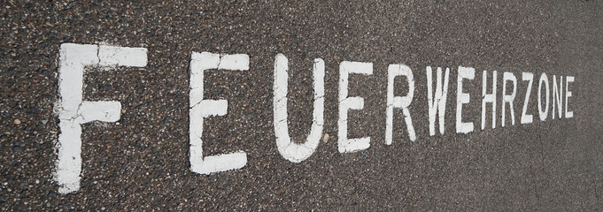 'Feuerwehrzone' is painted on the pavement in a parking area. It's German for fire lane. Only vehicles of the Fire department are allowed to park here
