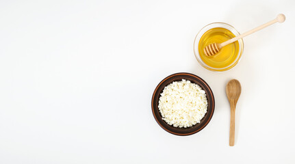 A healthy breakfast rich in vitamins and proteins in a clay bowl. Organic farmer's cottage cheese in a clay bowl with a wooden spoon. Natural fresh honey in a glass bowl with a honey ladle. Healthy
