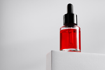 Essential oil bottle on gray block against gray background