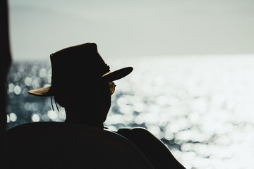 SILHOUETTE OF YOUNG MAN WITH HAT AT SUNSET ON THE BEACH