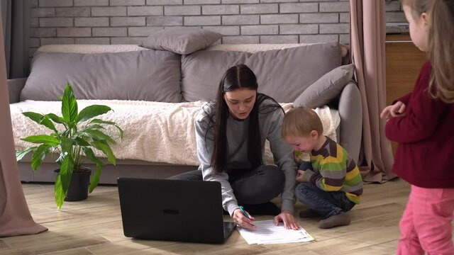 A multitasking mom working remote is stressed out. Problems associated with work at home. Noisy active kids boy and girl playing. Mother Work, Telecommute Flexible Job