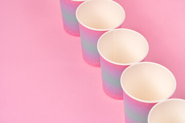 Pink disposable paper cups on pink background