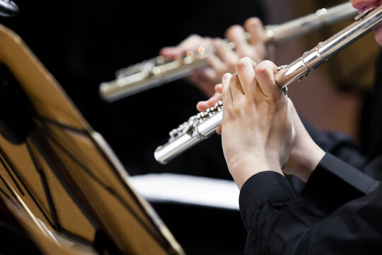  Hands of a musician playing the flute in an orchestra