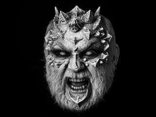Evil face with dragon skin and grey beard. Demon baring teeth isolated on black. Horror and fantasy...