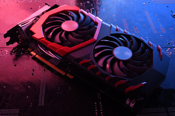 Computer game graphics card, videocard with two coolers on circuit board ,motherboard background. Close-up. With red-blue lighting