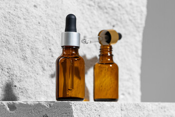 Glass jar of skincare serum on concrete block