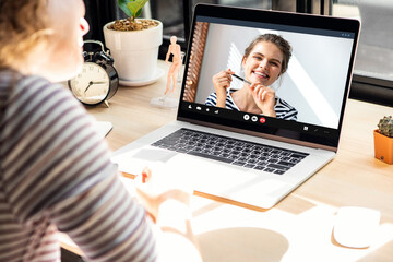 Smiling happy Caucasian woman chatting with female friend via online video call meeting using...