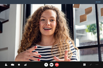 Happy pretty Caucasian woman smiling and  talking at the camera while making video call at home
