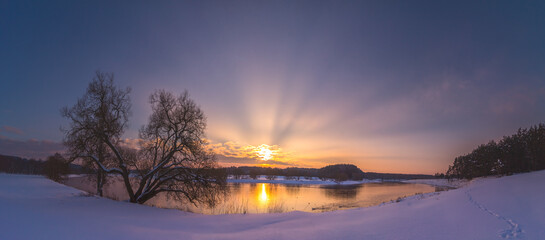 Winter evening landscape with sunrays in the sunset light