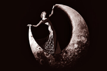 Fashion dream. Beautiful retro young woman with blonde hair posing on crescent moon in evening...