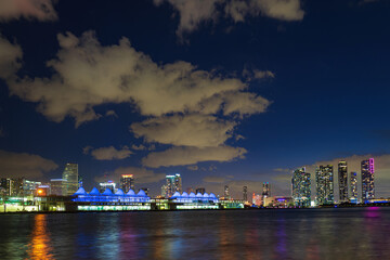 Naklejka premium Miami night downtown, city Florida. Miami city skyline panorama with urban skyscrapers over sea with reflection.