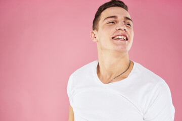 A man in a white t-shirt gestures with his hands emotions pink background studio cropped view