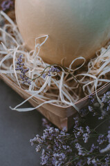 In a nest of hay lies a large fresh ostrich egg, decorated with purple flowers. Easter theme, holiday. Happy easter card with copy space for text in minimal easter style