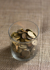 metal coins of different shapes, countries and values, in glass containers