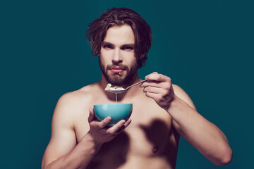 Morning healthy food and dieting, man with bare chest eating oatmeal. Breakfast cereal, healthy food for man or sport athlete.