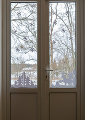 picture with window, window decorated with white paper ornaments, blurred view outside the window, winter