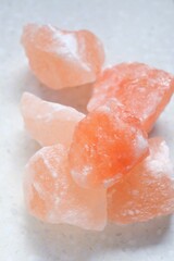 Pink himalayan salt pieces close-up on a light marble background.Pink crystal salt