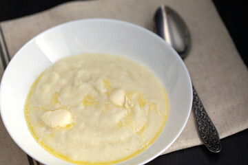 milk hot porridge or semolina pudding with butter and spoon on table. Breakfast is ready