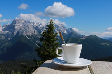 Primo piano di una tazzina da caffé con dietro una bellissima vista sulle montagne dal rifugio 5...