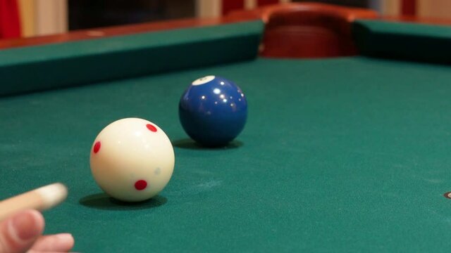 Closeup of Person Playing Pool Shooting Solid Blue 2 Ball into Corner Pocket after Practice Strokes using Cue Ball with Red Spots, Open Bridge Hand with Wooden Cue Stick and Green Felt or Cloth