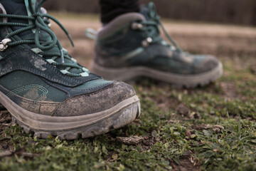 Women's trekking dirty boots in the grass and mud