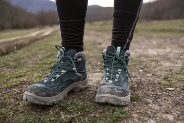 Women's trekking dirty boots in the grass and mud