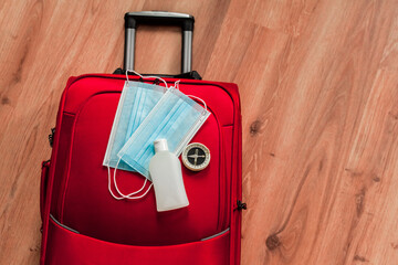 Antiseptic bottle and medical masks with compass on suitcase. Traveling and tourism worldwide during covid pandemic. Vacation or holiday in europe and america. flat lay top view copyspace background