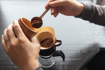 計量スプーンで挽きたてのコーヒーをドリッパーにセットしたペーパーフィルターに入れるところ