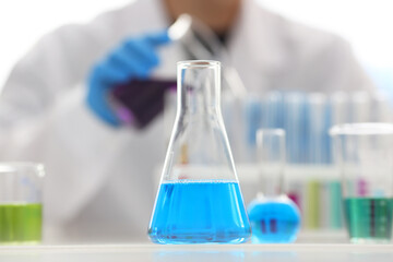 A male chemist holds test tube of glass in his hand overflows a liquid solution of potassium permanganate conducts an analysis reaction takes various versions of reagents using chemical manufacturing