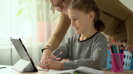 Cute children use laptop for education, online study, home studying, Boy and Girl have homework at distance learning. Lifestyle concept for home schooling. Mother helps daughter and son.