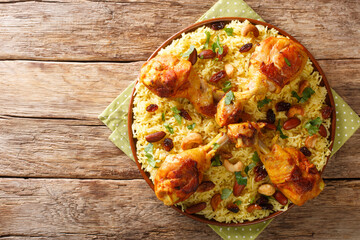 Homemade Arabic spiced rice and chicken topped with nuts, raisins closeup in the plate on the table. horizontal top view from above