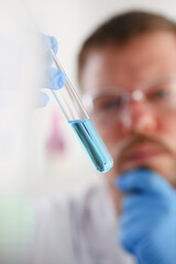 A male chemist holds test tube of glass in his hand overflows a liquid solution of potassium...