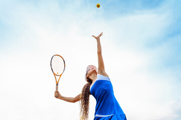 Tennis ball serving. Correct stance and practiced movements are essential for a good shot. A talented tennis player woman has been performing a well-trained movement for years. Ball up to the sky