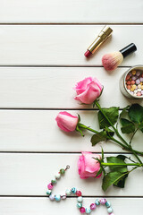 Top view arrangement with make-up, roses, necklace and copy-space on white wooden background