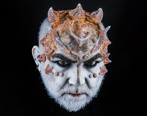 Head with thorns, close up. Demon, sorcerer makeup. Fantasy concept. Demon on serious face, black...