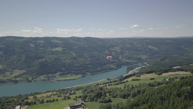 Aerial view of a person hang gliding over Norwegian nature - pan, drone shot
