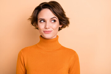 Photo of charming cunning young lady wear orange turtleneck looking empty space isolated beige color background