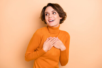 Photo of young happy positive lovely dreamy girl hear compliment hold hands chest isolated on beige...