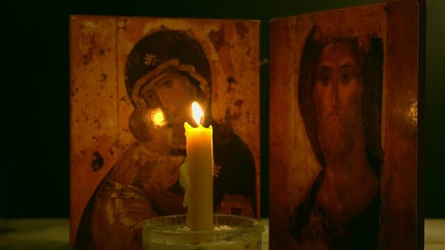 A church candle burns against the background of the icon, the Mother of God and Jesus Christ.