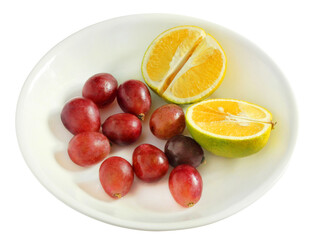 Grapes and cut oranges on white dish, isolated on white background
