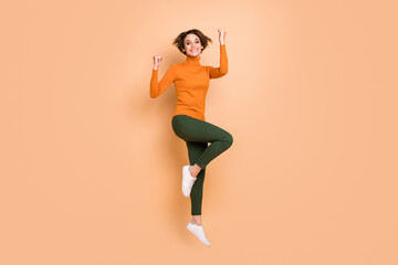 Fototapeta na wymiar Full size photo of young beautiful smiling cheerful happy smiling girl jump raise fists in victory isolated on beige color background