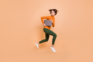 Fototapeta na wymiar Full size profile side photo of young scared afraid nervous stressed girl run in air hold laptop isolated on beige color background