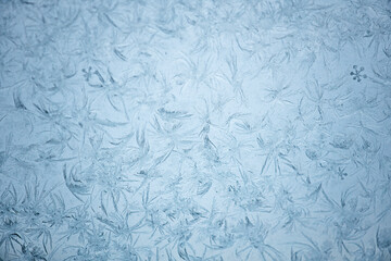 beautiful frosty pattern on a frozen window, fabulous ornament on glass in the winter season, focus in the center, edges blurred