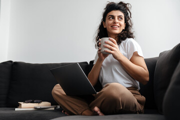 Happy brunette young woman working with laptop and drinking coffee