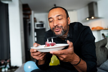 Happy middle aged man celebrating his birthday at home