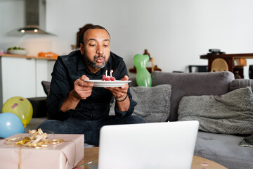 middle aged man blowing candles for his birthday at home