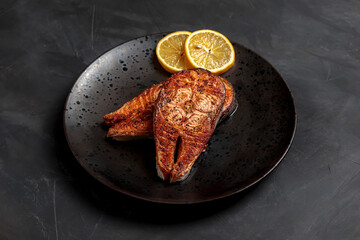 Salmon fish steak cooked. Dinner seafood dish plate. Grilled salmon with lemon, delicious lunch. Isolated roast fish portion, healthy bbq recipe, restaurant cuisine. Crispy Norwegian salmon, dark, top